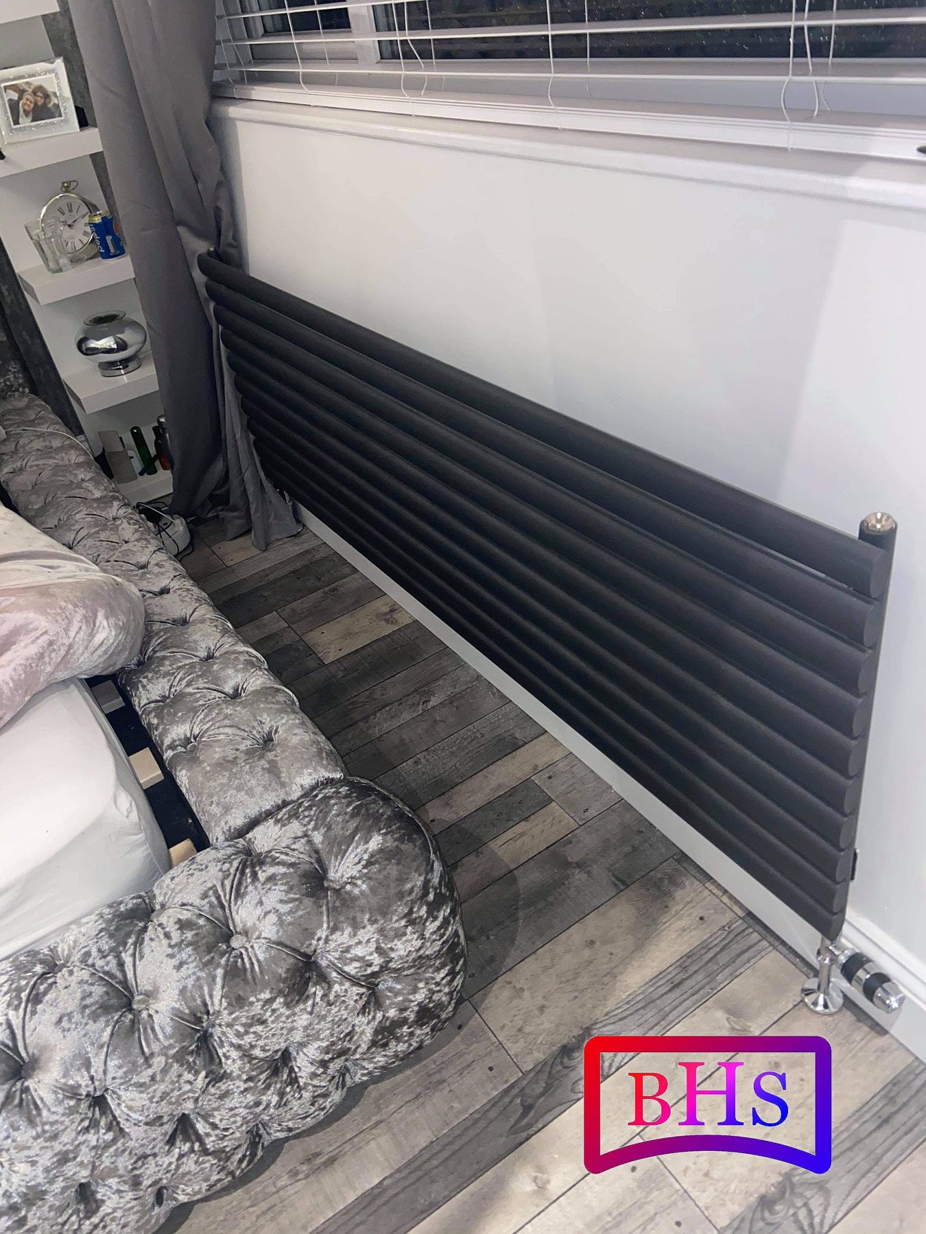 A black horizontal designer radiator fitted under a window