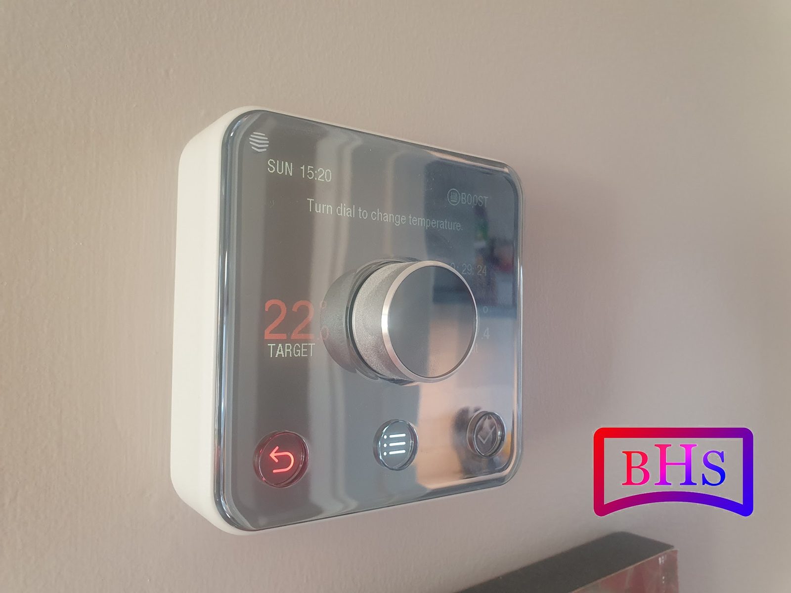 A smart thermostat on a living room wall set to 22 degrees